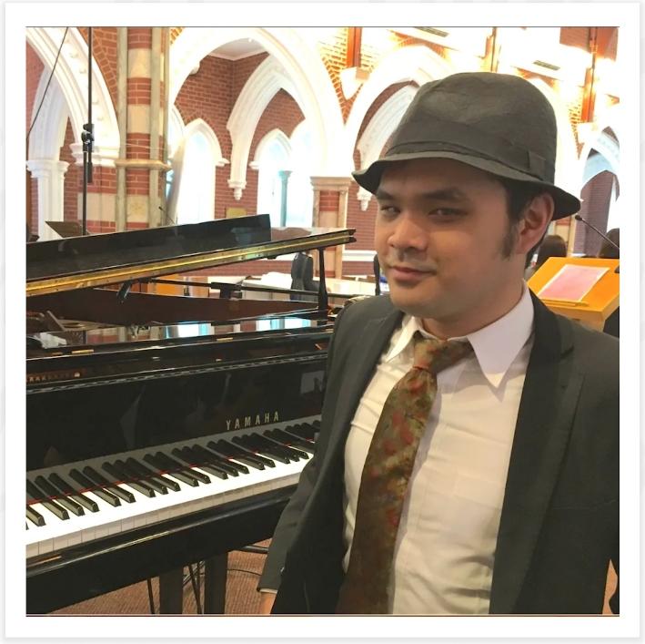 Timth 戴著帽子坐在鋼琴前的照片